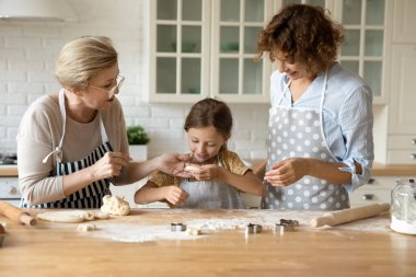 Mutlu büyükanne anne, küçük kıza kurabiye kesmeyi açıkla.