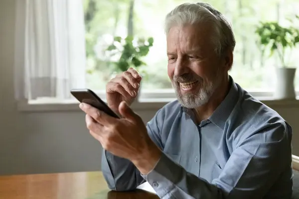 Video görüşmesi için akıllı telefonu kullanan 70 'li yaşlardaki mutlu yaşlı adam. — Stok fotoğraf