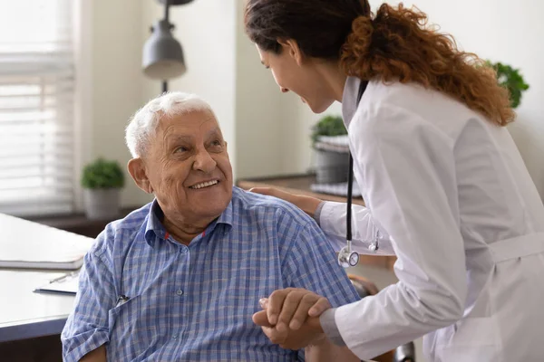 De cerca enfermera cariñosa sosteniendo sonriente mano paciente madura — Foto de Stock