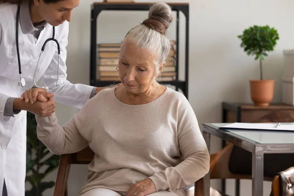 De cerca el cuidado médico femenino sosteniendo la mano de la mujer mayor — Foto de Stock