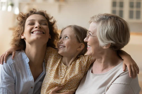 Família amorosa de três mulheres de idade diversificada abraço no sofá — Fotografia de Stock