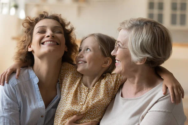 Familia cariñosa de tres mujeres de edad diversa abrazo en el sofá —  Fotos de Stock