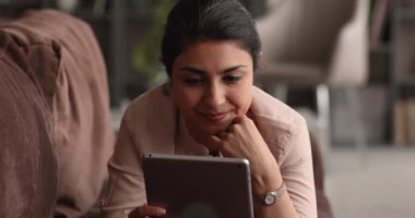 Dijital tablet kullanan hayalperest genç, mutlu Hintli kadın..