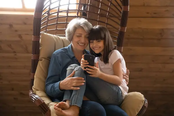 Happy senior grandmother and granddaughter use smartphone laughing — Stock Photo, Image