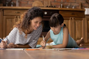 Sevgi dolu genç anne ve küçük kızı birlikte çiziyorlar.