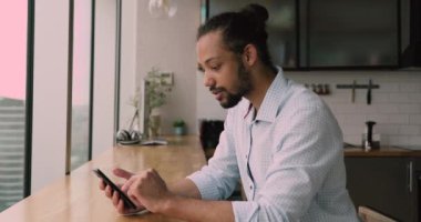 Gülümseyen Afrikalı genç adam akıllı telefon kullanmaktan zevk alıyor..