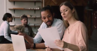 Konsantre genç beyaz kadın Afrikalı meslektaşımla raporları tartışıyor..