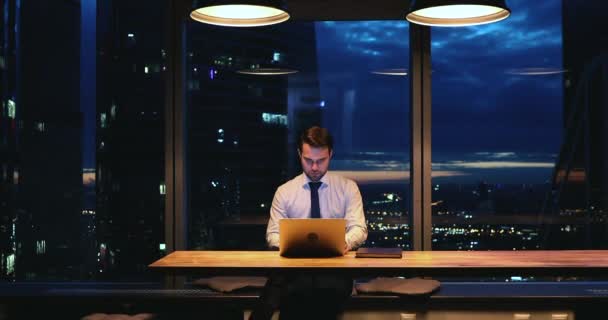 Pensativo joven hombre de negocios que trabaja en la computadora tarde. — Vídeos de Stock