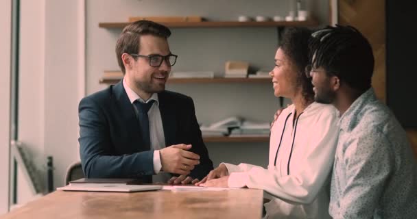 Lachen aangename jonge professionele makelaar schudden handen met Afrikaanse klanten. — Stockvideo