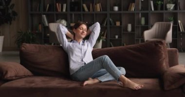 Mutlu, genç, güzel bir kadın, yalınayak koltukta dinleniyor..