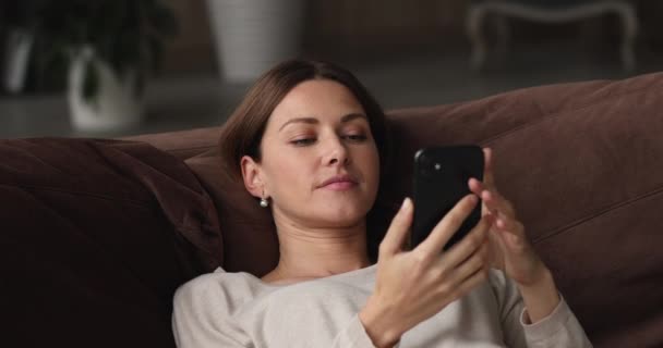Relaxált boldog fiatal nő használ okostelefon otthon. — Stock videók