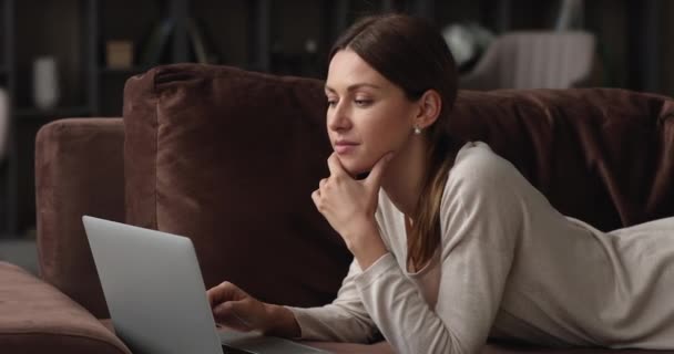 Soñador joven mujer caucásica utilizando la aplicación portátil. — Vídeos de Stock