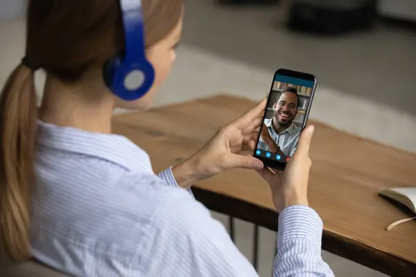 Kulaklık takan beyaz bir kadın cep telefonundan web kamerasına bağlanıyor. — Stok fotoğraf