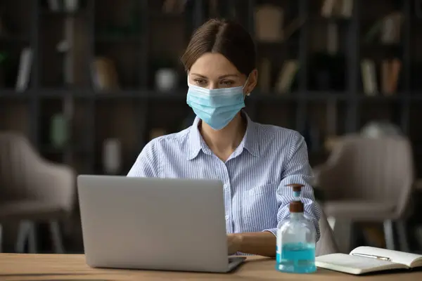 Caucasian businesswoman wear facemask work on laptop — Stock Photo, Image