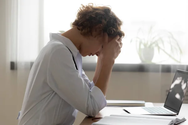 Unavený lékař trpí bolestí hlavy na pracovišti — Stock fotografie
