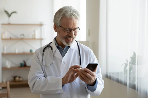 Usmívající se starší lékař pomocí moderního mobilu — Stock fotografie