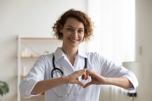 Portret uśmiechniętej kobiety lekarz pokazać znak miłości — Zdjęcie stockowe
