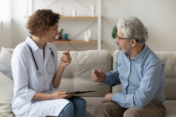 Caring female doctor consult elderly patient at home