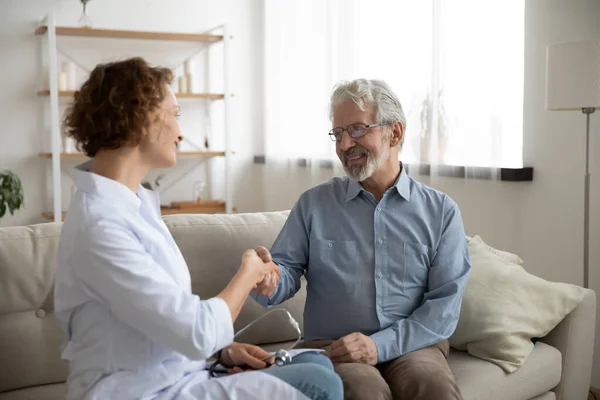 Smiling female doctor handshake with senior male patient — Stock Photo, Image