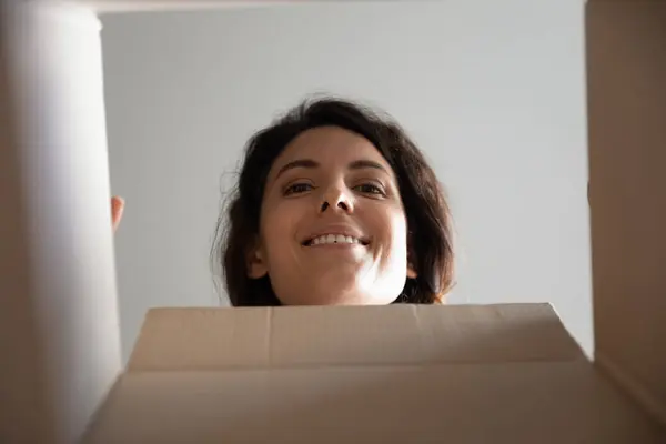 Curious millennial female face look inside cardboard box postal parcel — Stock Photo, Image