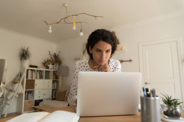 Evden bilgisayarda düşünceli bir kadın çalışması. Ekrana bak.