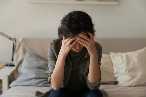 Frustrated depressed millennial woman sit on couch alone hug head — Stock Photo, Image