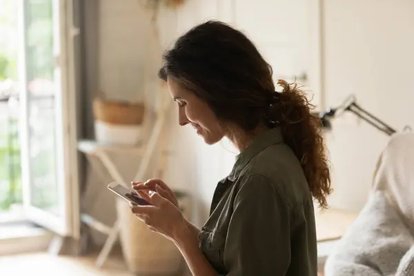 Uśmiechnięta młoda kobieta wygląd na ekranie telefonu mając randkę online — Zdjęcie stockowe