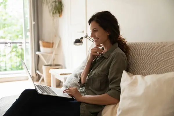 Le tusenårig kvinna sitta på soffan håll bärbar dator chatt online — Stockfoto