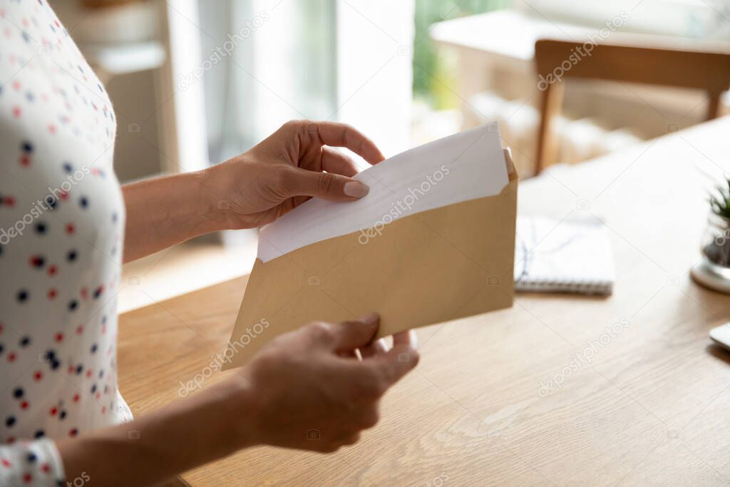 Female hands put letter in envelop before send by mail