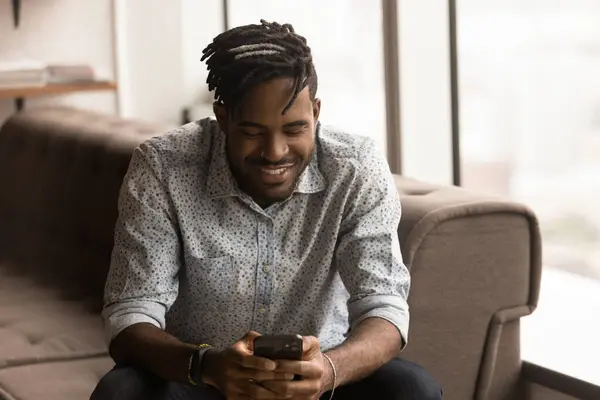 Närbild leende afroamerikansk man håller telefonen, bläddra appar — Stockfoto