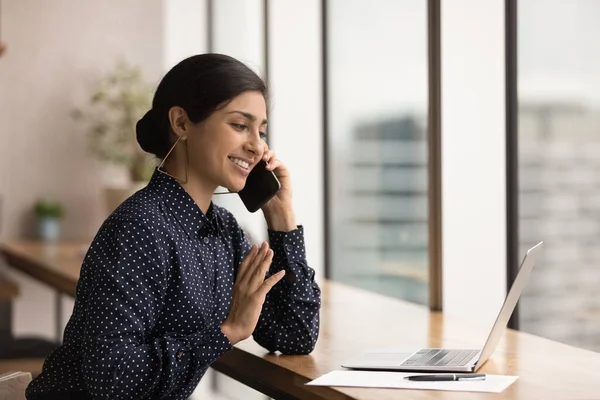 Close up smiling Indian woman talking on phone, using laptop — Stock Photo, Image