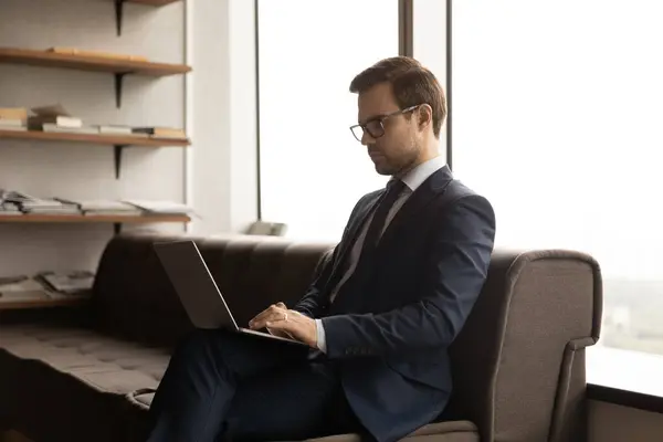 De cerca empresario seguro de usar gafas y traje usando el ordenador portátil — Foto de Stock