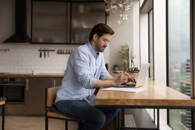 Gözlüklü kendine güvenen iş adamı evde dizüstü bilgisayar kullanıyor