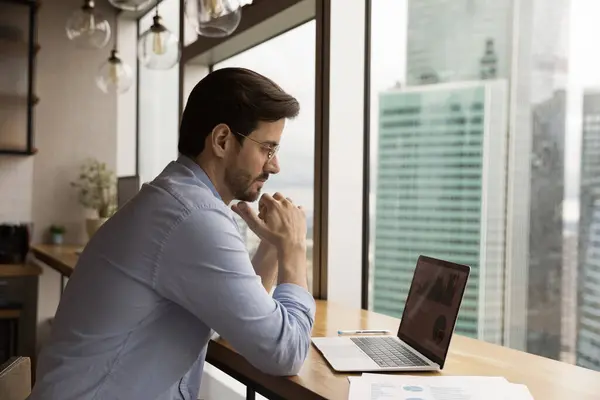 Primer plano pensativo hombre de negocios con gafas mirando a la pantalla del ordenador portátil —  Fotos de Stock