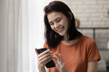 Genç bayan oturma odasında akıllı telefondan çalışıyor.