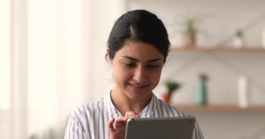 Dokunmatik ekranlı dijital bilgisayar tableti kullanan gülümseyen Hintli etnik kadın..