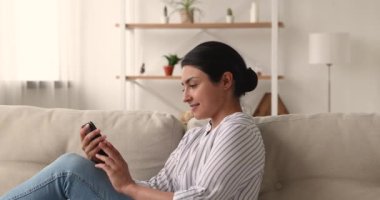 Evde akıllı telefon kullanan mutlu Hintli genç kadın..