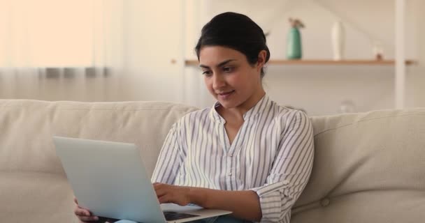 Relaks uśmiechnięta wielorasowa kobieta za pomocą laptopa w pomieszczeniach. — Wideo stockowe