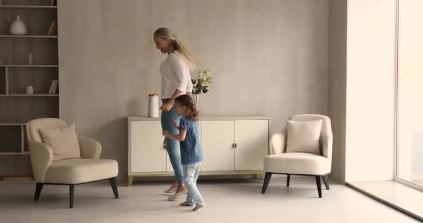 Tanara mama dansand cu fiica mica in camera de zi moderna — Videoclip de stoc