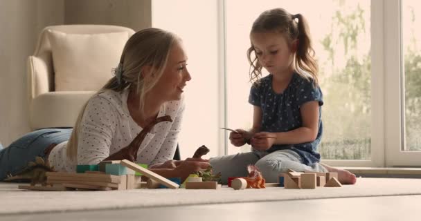 Jonge vrouw spelen dinosaurus speelgoed set met weinig schattig dochter — Stockvideo