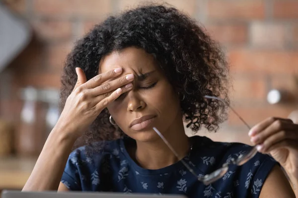 Frustrado negro freelancer femenino sobrecargado de trabajo por ordenador siente dolor de cabeza migraña — Foto de Stock