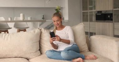 Akıllı telefon web sörfü interneti kullanarak rahat koltukta oturan bir kadın.