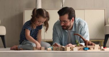 Baba ve küçük kız oturma odasında tahta küplerle oynuyorlar.