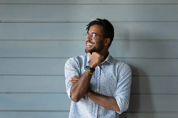 Homme africain millénaire souriant posant contre le mur gris détourner les yeux — Photo