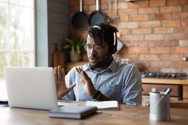 Nero uomo esperto in cuffie assistere client online utilizzando il computer portatile — Foto Stock