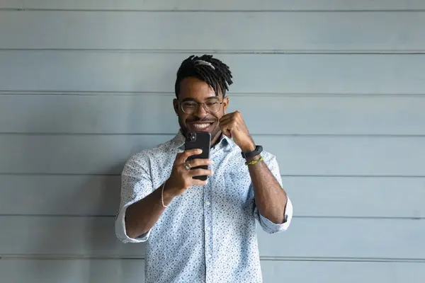 Tur ung afrikansk man titta på mobiltelefon skärmen fira seger — Stockfoto