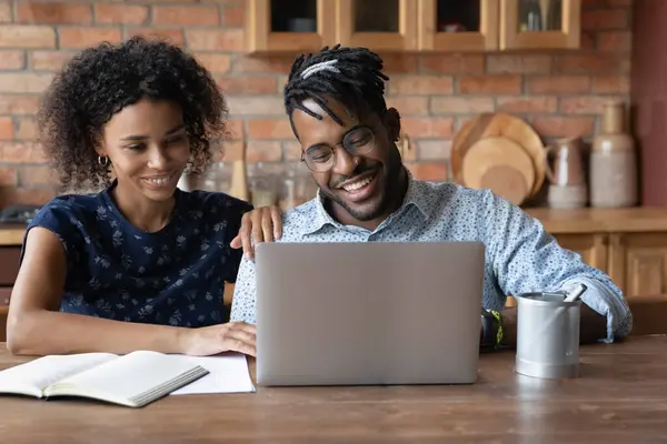Mosolygó fekete férj nézd meg a laptop képernyőn konzultáljon a feleségével — Stock Fotó