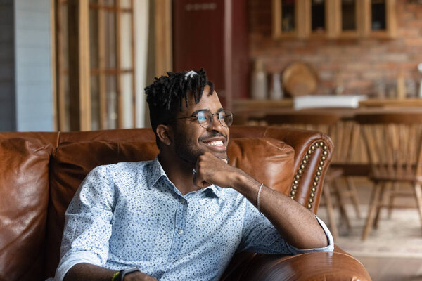 Happy young african man relax on couch enjoy good day
