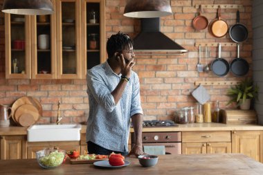Gülümseyen bin yıllık zenci erkek hippi yemek pişiriyor. Telefonlara cevap veriyor.