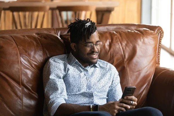 Glada tusenåriga afrikanska killen student spela smartphone baserat online-spel — Stockfoto